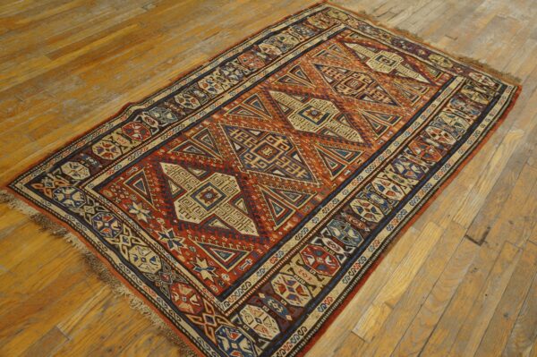 Geometric area rug featuring rust, navy, and tan patterns on rustic hardwood floors.