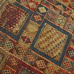 A colorful, flatweave, geometric pattern featuring complex diamonds in red, deep blue, gold, and orange threads.