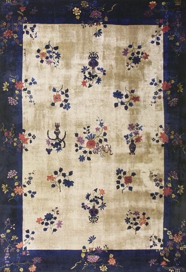 Low-pile beige rug framed by a dark navy border, patterned with ornate multicolor floral clusters.