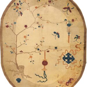 Oval beige rug with a brown border and detailed traditional pattern of flowering vines, lanterns, and symbols.