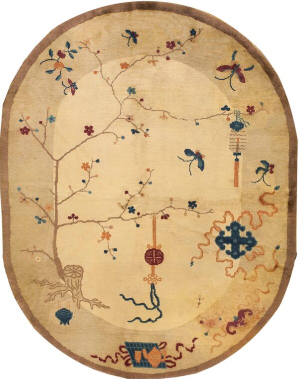 Oval beige rug with a brown border and detailed traditional pattern of flowering vines, lanterns, and symbols.