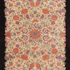 Dense multicolored floral rug on a light beige field, featuring a decorative scalloped edge on black.