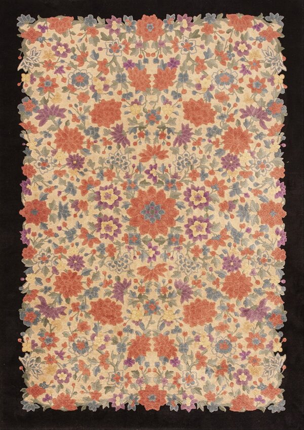Dense multicolored floral rug on a light beige field, featuring a decorative scalloped edge on black.