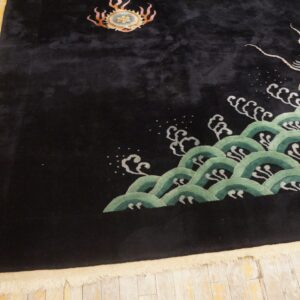 Plush black rug displaying a gold dragon pattern rising from stylized green waves on distressed wood flooring.