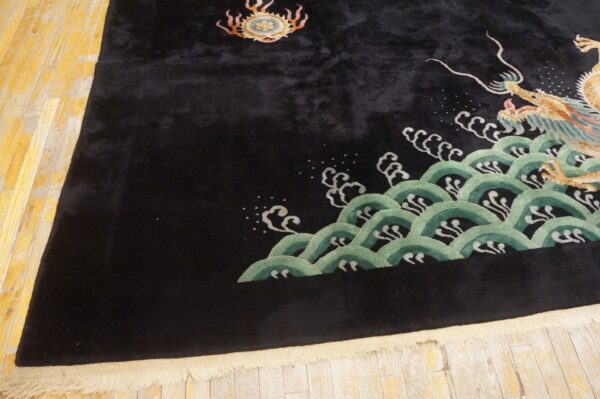 Plush black rug displaying a gold dragon pattern rising from stylized green waves on distressed wood flooring.