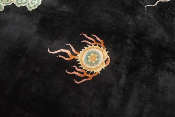 Plush black rug with a stylized yellow and blue medallion surrounded by pink and orange tendrils.