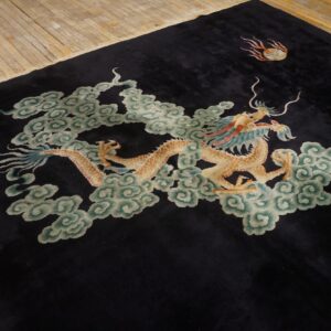 Medium pile black rug with a golden dragon and blue-green clouds on rustic hardwood flooring.