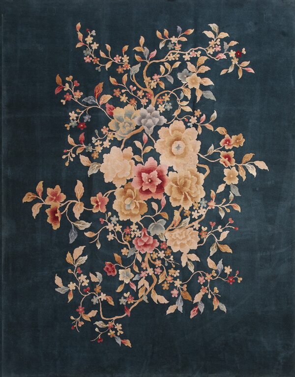 A dark teal rug features a large, central spray of pink, cream, and gold flowers and intertwining branches.