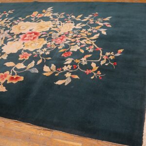 Plush dark teal rug featuring large cream and pink floral motifs rests on rustic wood planks.