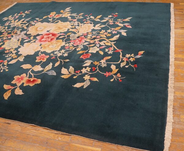 Plush dark teal rug featuring large cream and pink floral motifs rests on rustic wood planks.