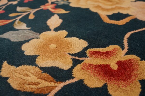 Gold and red floral motif on a dense, dark teal pile rug surface.