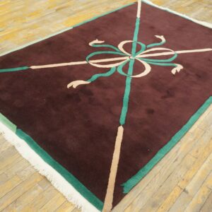 Maroon rug with a high pile and a central teal and cream ribbon motif on wood flooring.