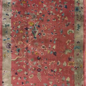Low-pile rug with a lustrous dusty rose field and taupe border, covered in multicolored floral motifs.