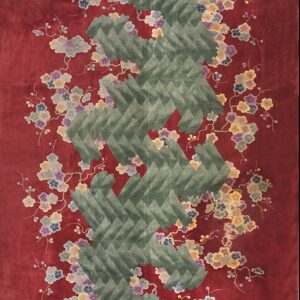 Deep red rug with lush multicolored flowers surrounding a prominent carved green chevron motif.