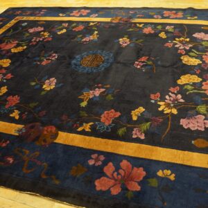 Navy area rug with intricate floral pattern in pink, yellow, and red, framed by a golden yellow border.