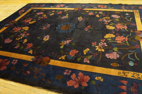 Navy area rug with intricate floral pattern in pink, yellow, and red, framed by a golden yellow border.