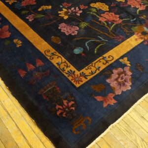 Navy floral rug with a bright gold border lies on bright yellow hardwood planks.