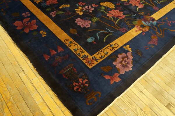 Navy floral rug with a bright gold border lies on bright yellow hardwood planks.