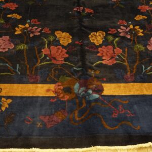 Dark blue plush rug showing colorful stylized flowers and a prominent saffron-colored main border.