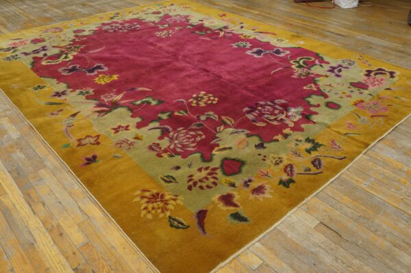 Large magenta rug with mustard yellow and pale green floral borders on worn wooden floorboards.