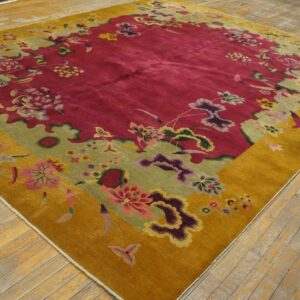 Large floral rug in deep pink, sage green, and mustard gold on light-colored wood flooring.