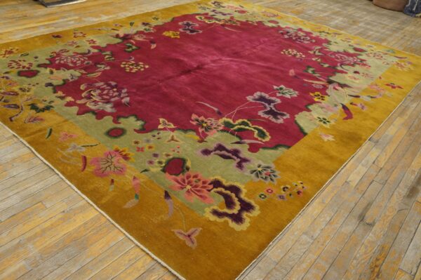 Large floral rug in deep pink, sage green, and mustard gold on light-colored wood flooring.