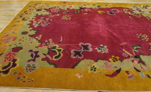 Ornate floral rug with a deep red field and complex green and mustard borders on a light wood floor.