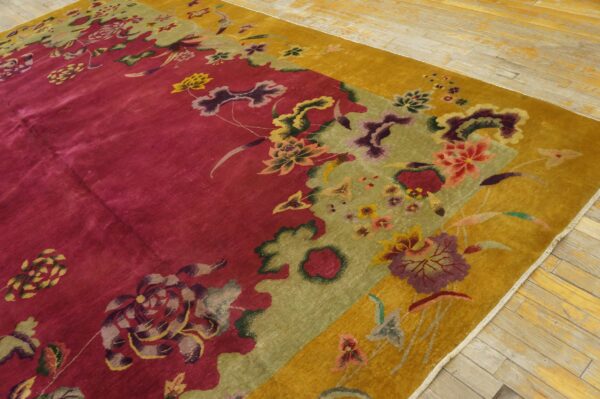 Deep magenta rug with gold and green borders featuring large stylized floral patterns on light wood floor.