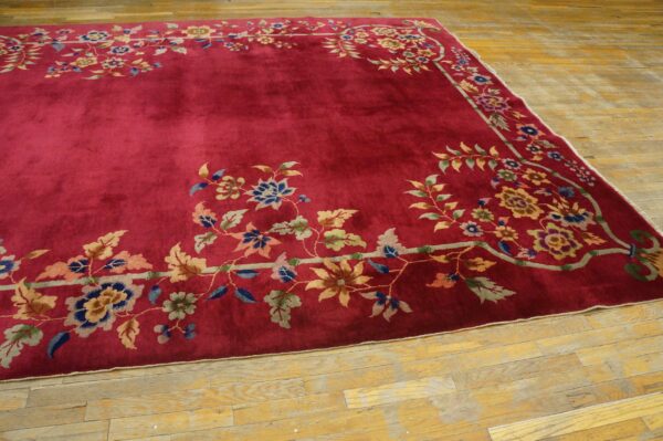 High-pile magenta rug featuring a detailed multicolored floral border on a rustic wooden floor.