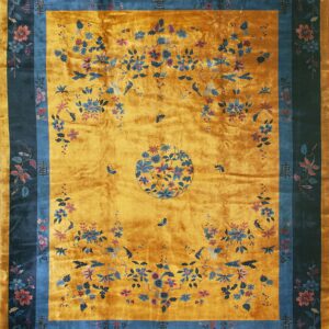 Reflective gold rug with a dark border, featuring sprawling blue, pink, and mauve floral vine patterns.