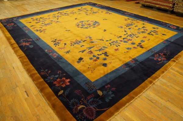 Yellow high-pile rug with navy and teal borders, featuring scattered florals on a distressed wooden floor.