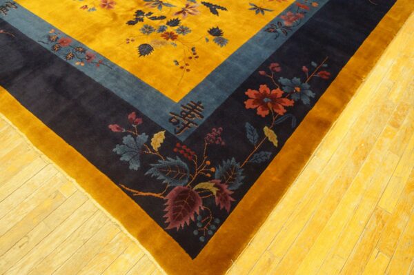 Deep pile yellow rug with blue and navy stepped borders, detailed florals, resting on wood planks.