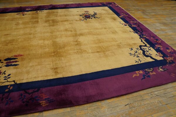 Yellow gold rug with magenta and navy borders featuring chinoiserie floral patterns on wood flooring.