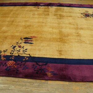 Plush golden rug with wide plum and navy borders features scattered floral patterns on light wood flooring.