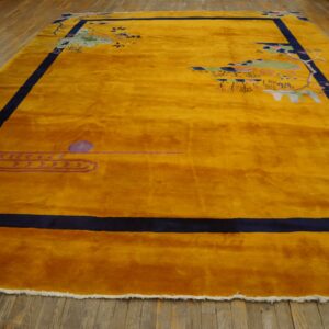 Plush gold rug with navy blue border and scattered Asian motifs lays on rustic wood planks.
