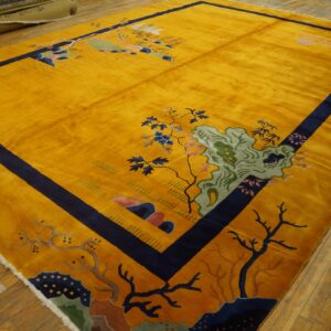 Shimmering gold rug with a navy border and detailed landscape pattern rests on distressed wood flooring.