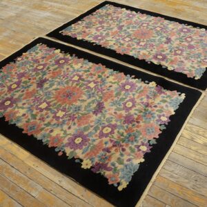 Matching rugs with dense, multicolored floral patterns and solid black borders rest on worn wood flooring.