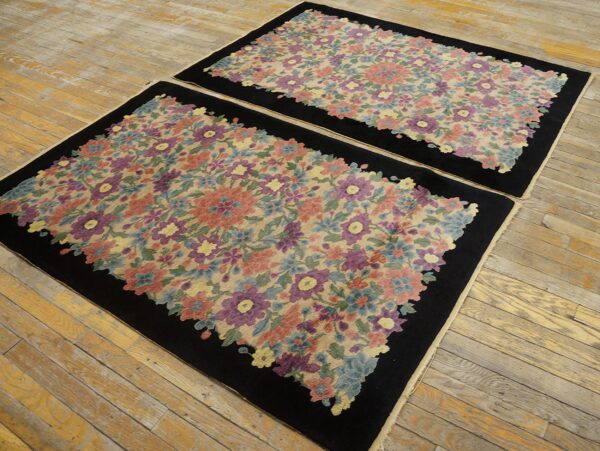 Matching rugs with dense, multicolored floral patterns and solid black borders rest on worn wood flooring.