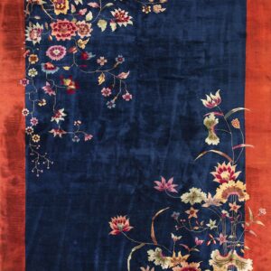 Deep blue rug featuring a vibrant multicolored floral vine design and a wide reddish-orange border.