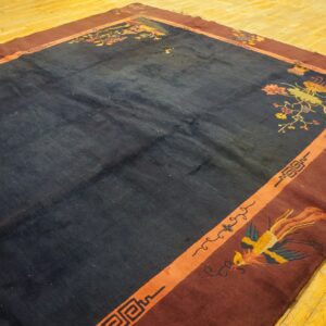 Navy rug with maroon borders and floral patterns lies on bright yellow wood flooring.
