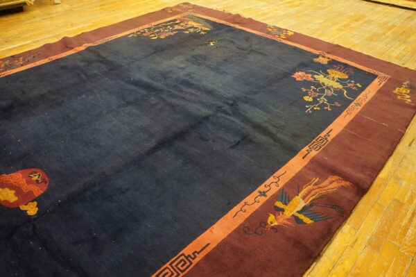 Navy rug with maroon borders and floral patterns lies on bright yellow wood flooring.