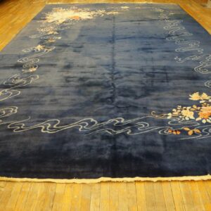 Deep blue high-pile rug featuring a border of white waves and pale orange floral patterns on wood planks.