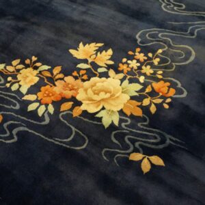 Navy blue rug displays a detailed cluster of yellow and orange flowers with pale gray flowing lines.