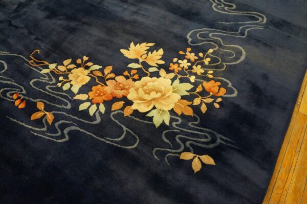 Navy blue rug displays a detailed cluster of yellow and orange flowers with pale gray flowing lines.