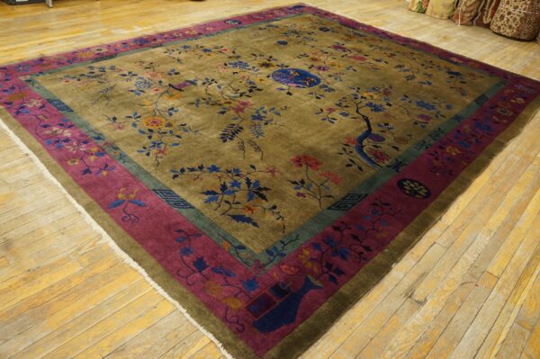 Multi-colored floral rug with an olive field and wide magenta border lying on light-toned wood flooring.