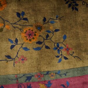 High-pile rug featuring blue and orange floral design on an olive field with pink and sage green borders.
