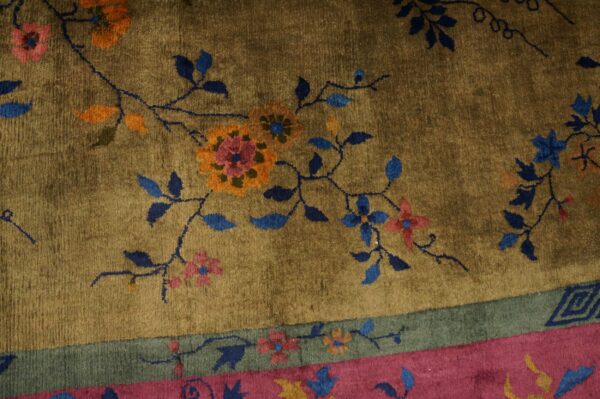 High-pile rug featuring blue and orange floral design on an olive field with pink and sage green borders.