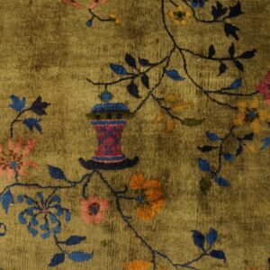 High-pile olive rug with a stylized vase, bird, and pink and blue flowering vine pattern.