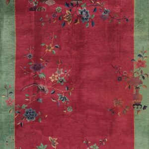 High-pile red rug with a wide green border and detailed floral, vase, and bird patterns.