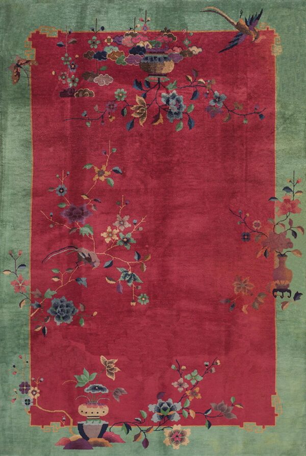 High-pile red rug with a wide green border and detailed floral, vase, and bird patterns.